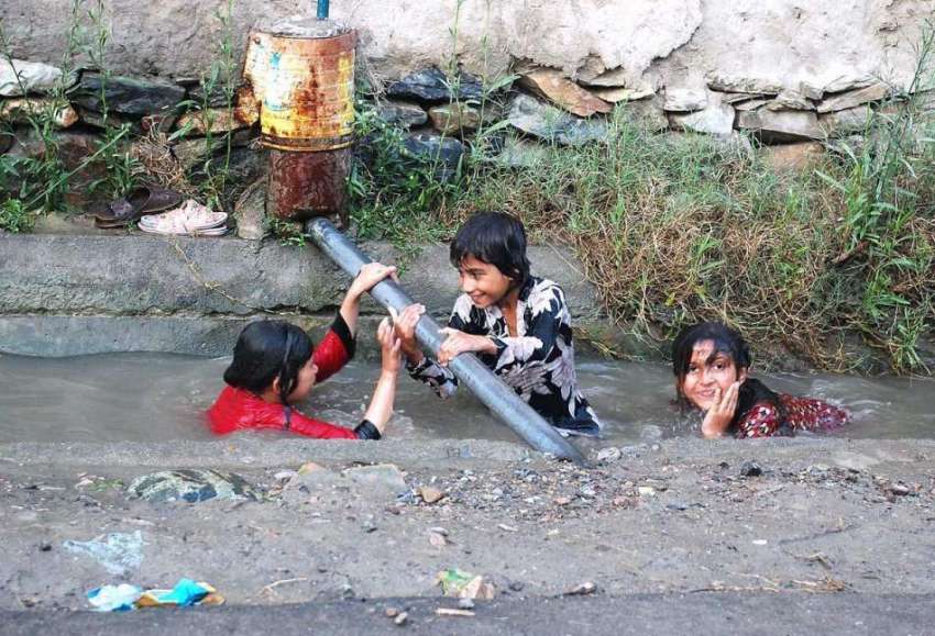 پشاور: گرمی کی شدت کم کرنے کے لیے بچے نالے میں نہا رہے ہیں۔