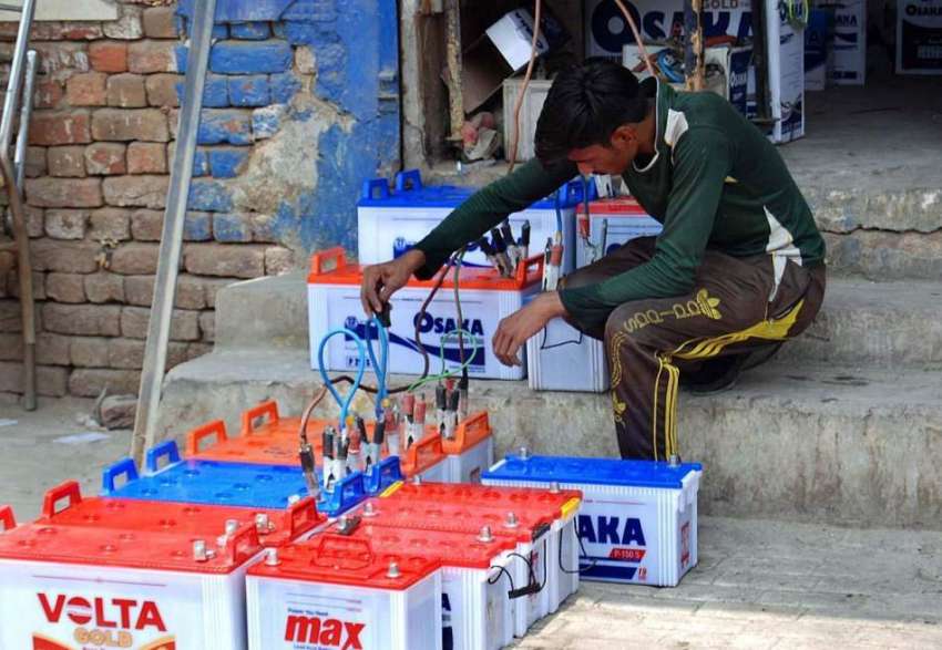 فیصل آباد: مزدور بیٹریاں چارج کرنے میں مصروف ہے۔