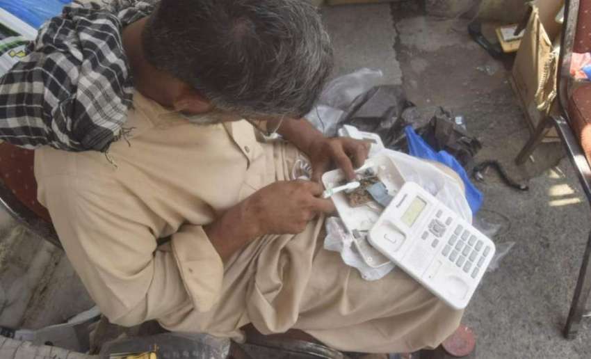 لاہور: ایک کاریگر ٹیلی فون مرمت کرنے میں مصروف ہے۔