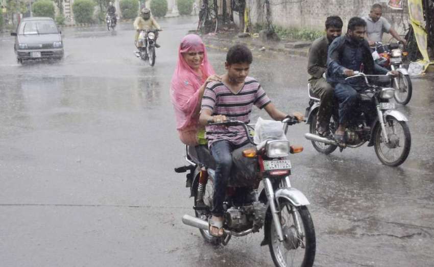 لاہور: شہر میں ہونیوالی بارش کے دوران شہری اپنی منزل کی جانب ..