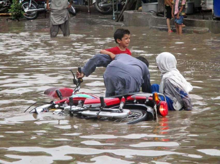 فیصل آباد: بارش کے بعد جمع ہونے والے پانی میں ایک موٹر سائیکل ..