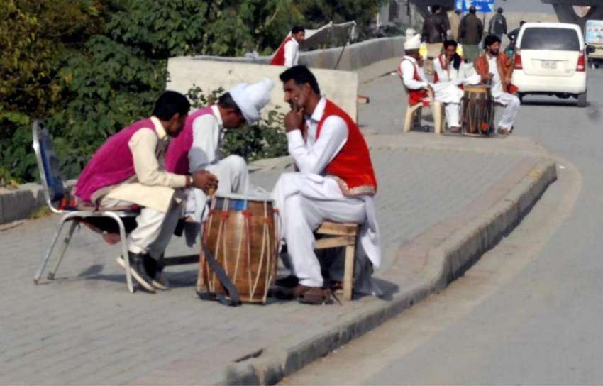 راولپنڈی: ڈھولچی کام کے انتطار میں روڈ کنارے دھوپ پر بیٹھے ..