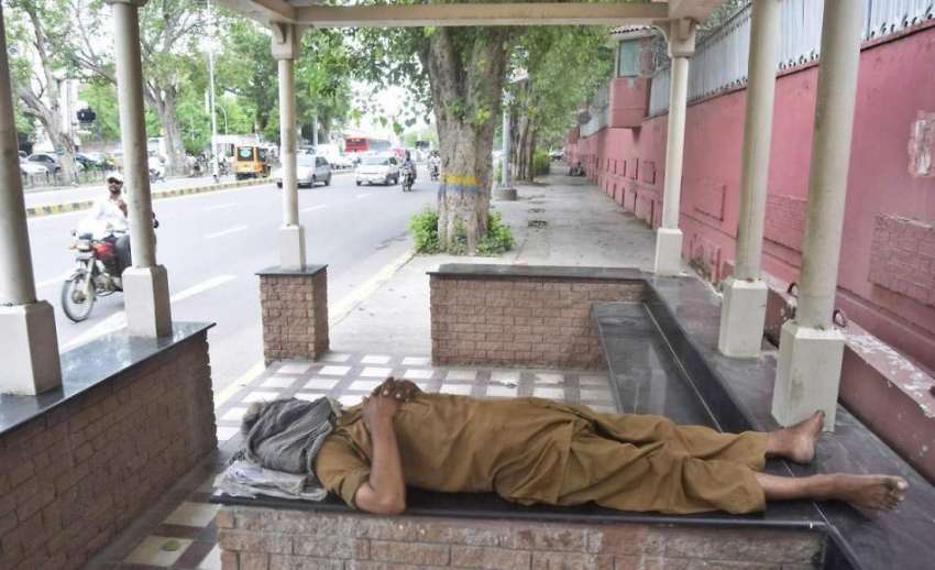 لاہور: مال روڈ پر بنے بس سٹاپ میں ایک شخص دوپہر کے وقت نیند ..