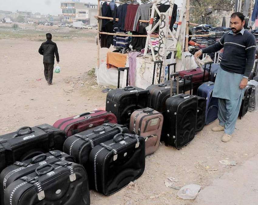 راولپنڈی: محنت کش رو ڈ کنارے سوٹ کیس فروخت کے لیے سجارہا ..