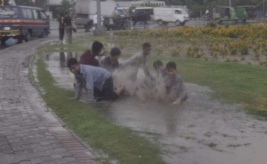 لاہور: مینارپاکستان کے قریب بچے سڑک کنارے بارش کے گندے پانی ..
