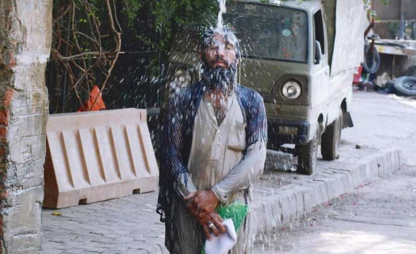 لاہور: ایک شخص گرمی کی شدت کم کرنے کے لیے واسا کے نل کے نیچے ..