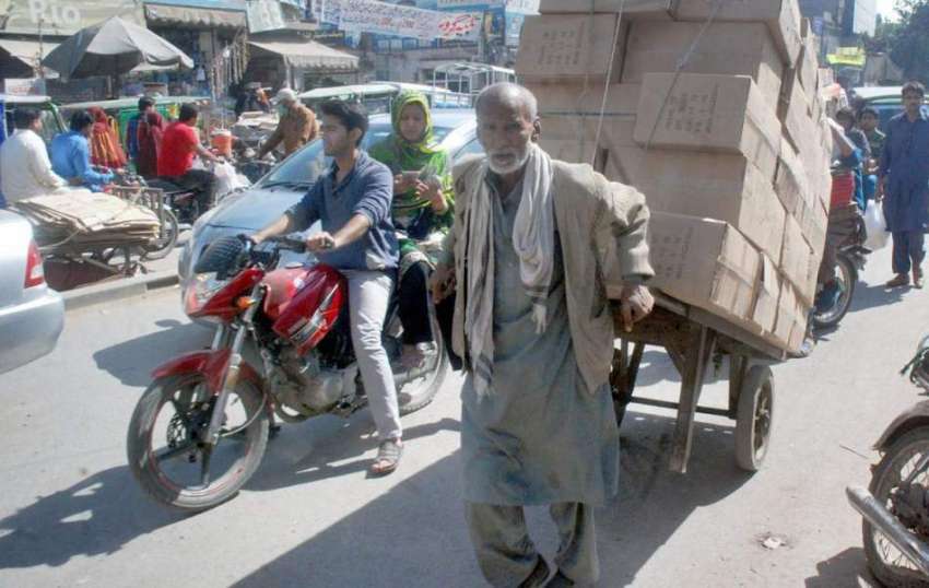 لاہور: ایک بزرگ محنت کش ہتھ ریڑھی پر بھاری سامان رکھ کر لیجا ..