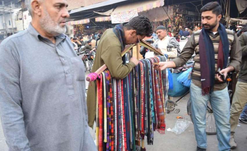 لاہور: ایک نوجوان سردی سے بچنے کے لیے مفرل خرید رہا ہے۔
