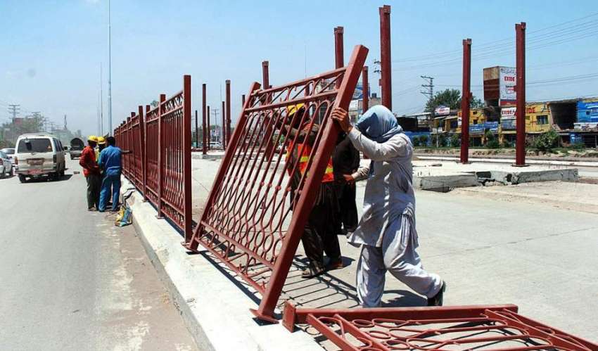 پشاور: مزدور حاجی کیمپ کے قریب سڑک کنارے لوہے کی باڑ لگانے ..