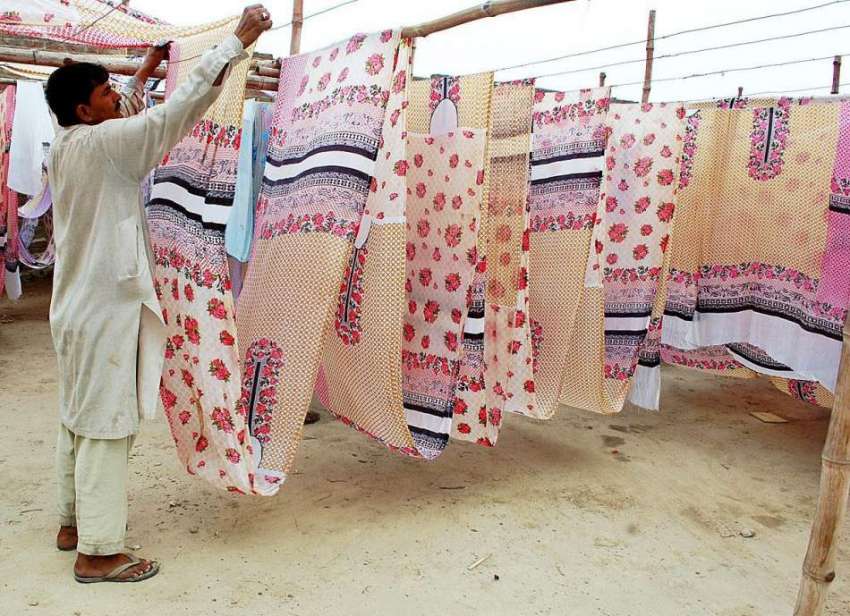 حیدر آباد: فیکٹری کا مزدور کپڑا خشک کرنے کے لیے دھوپ میں ..