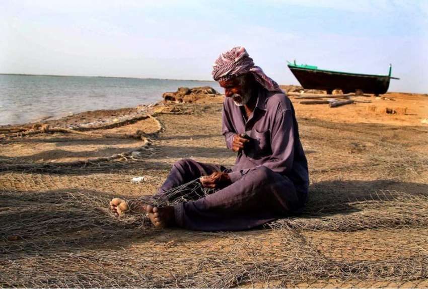 حیدر آباد: ایک معمر ماہی گیر مچھلیاں پکڑنے والا جال بنا رہا ..