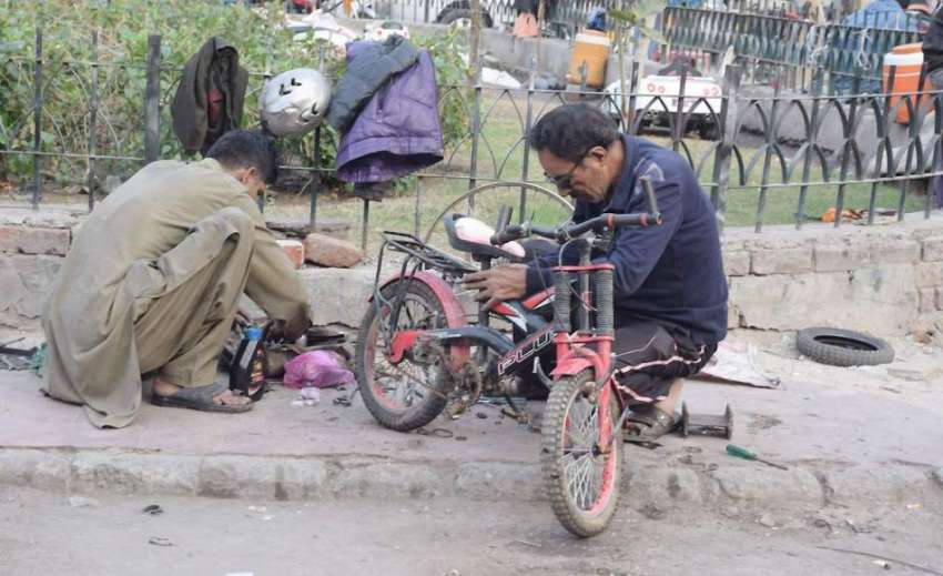 لاہور: ایک کاریگر نیلا گنبد میں سائیکل مرمت کررہا ہے۔