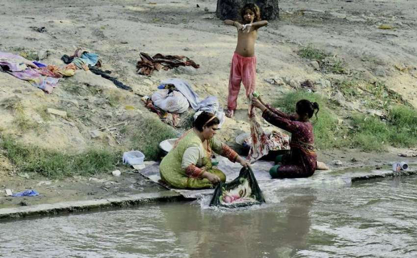 لاہور: خانہ بدوش خواتین نہر کنارے بیٹھی کپڑے دھو رہی ہیں۔
