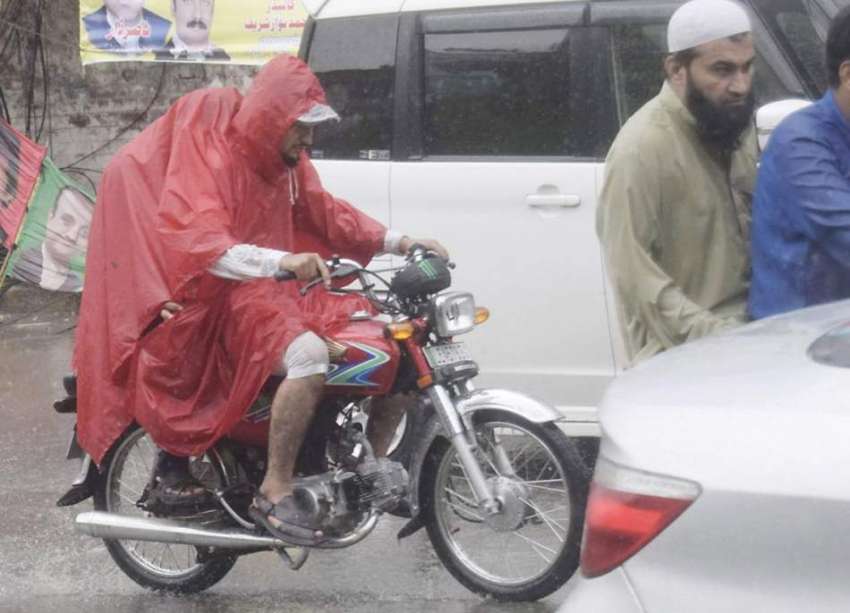 لاہور: شہر میں ہونیوالی بارش کے دوران موٹر سائیکل سوار برساتی ..