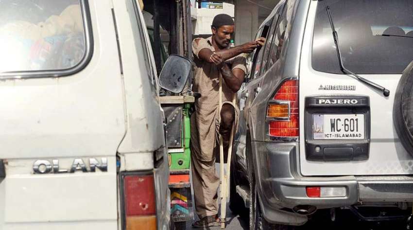 راولپنڈی: ٹریفک سگنل پر ایک معذور شخص بھیک مانگ رہا ہے۔