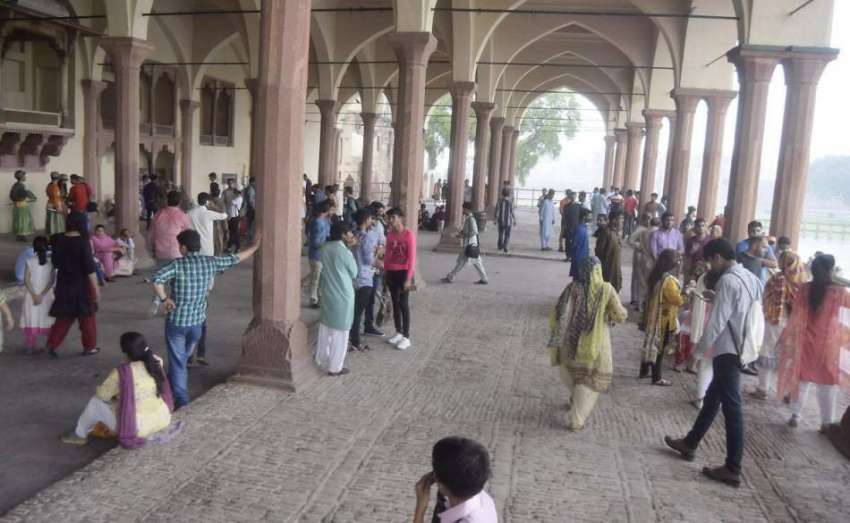لاہور: شاہی قلعہ میں سیرو تفریح کے لیے آئے شہری بارش سے بچنے ..
