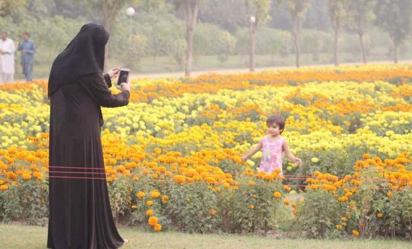 لاہور: جیلانی پارک میں ایک خاتون اپنی بچی کی پھولوں کے پاس ..