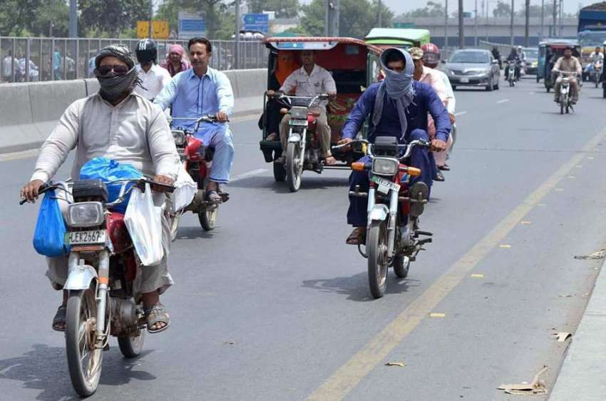 لاہور: موٹر سائیکل سوار گرمی کی شدت سے بچنے کے لیے منہ پر ..