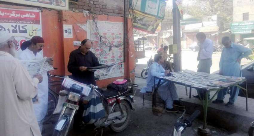 لاہور: شہری گڑھی شاہو چوک میں ایک سٹال سے اخبار پڑھ رہے ہیں۔