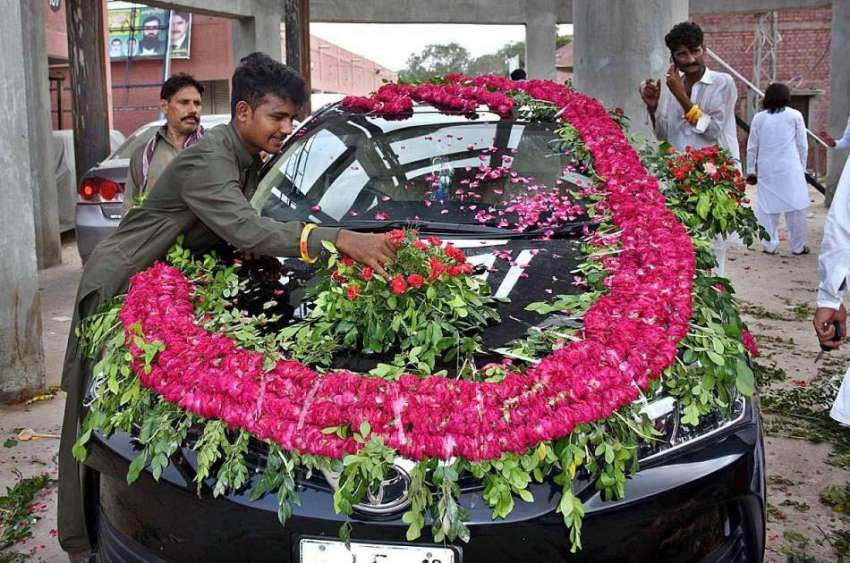 لاہور: مزدور کار کو پھولوں سے سجا رہے ہیں۔