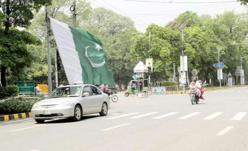 لاہور: یوم آزادی کے موقع پر گاڑی میں سوار شہری بڑے سائز کا ..