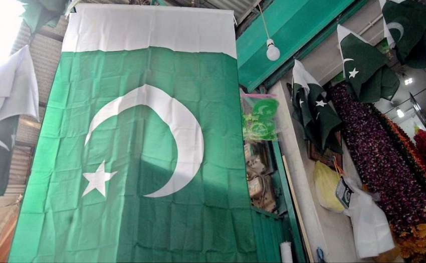 راولپنڈی: یوم آزاد کی آمد کے موقع پر ایک دکاندر قومی پرچم ..