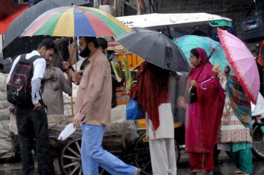 راولپنڈی: راجہ بازار میں خواتین چھتری تھامے بارش رکنے کا ..