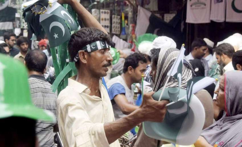 لاہور: اردو بازار میں ایک شخص یوم آزادی کی مناسبت سے اشیاء ..