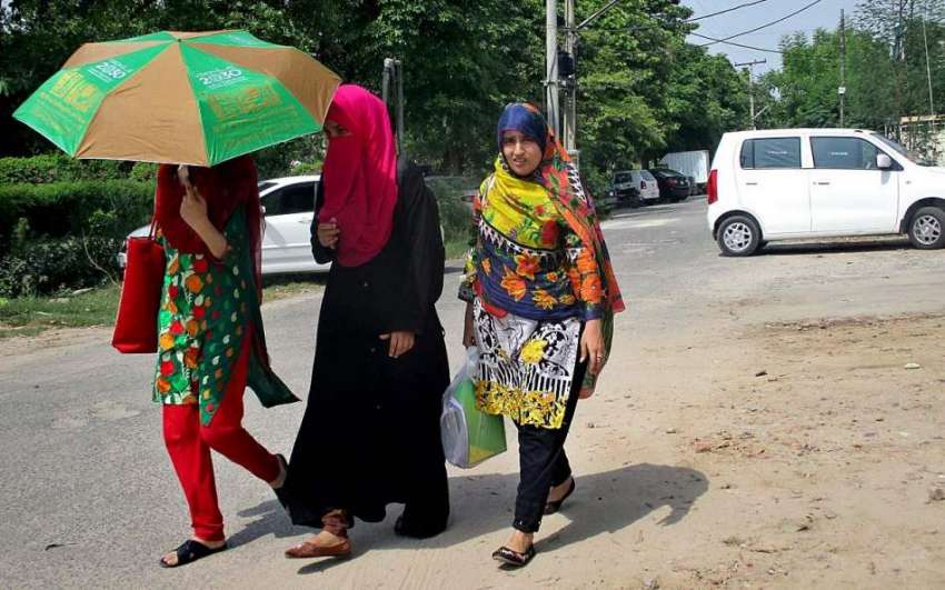 فیصل آباد: خواتین گرمی اور دھوپ کی شدت سے بچنے کے لیے چھتری ..