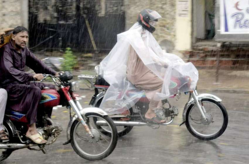 لاہور: شہر میں ہونیوالی بارش کے دوران ایک موٹر سائیکل سوارپلاسٹک ..