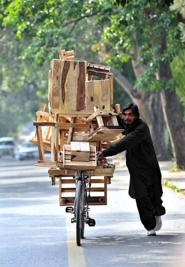 اسلام آباد: محنت کش سائیکل پر لکڑی کے سٹول رکھے فروخت کے ..