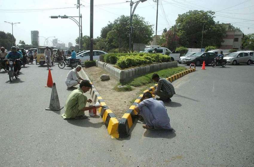 کراچی: مزدور کورنگ روڈ پر سیمنٹ کے بلاک کو پینٹ کر رہے ہیں۔