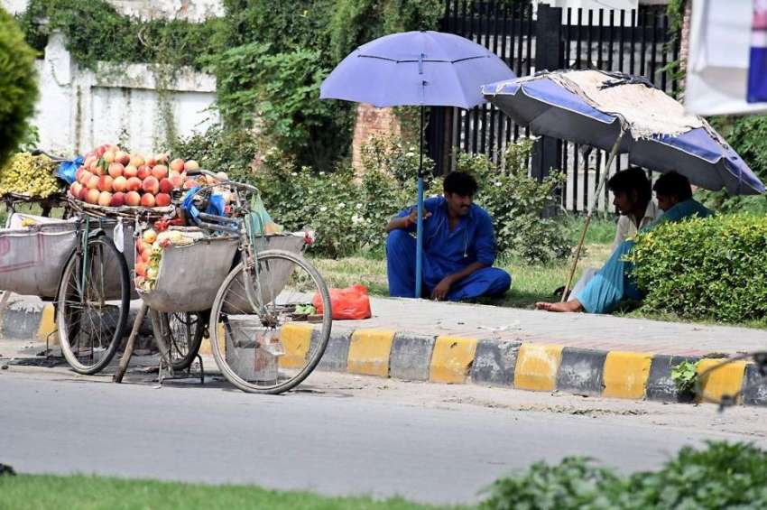 راولپنڈی: کچہری روڈ پر محنت کش دھوپ سے بچنے کے لیے چھتری ..
