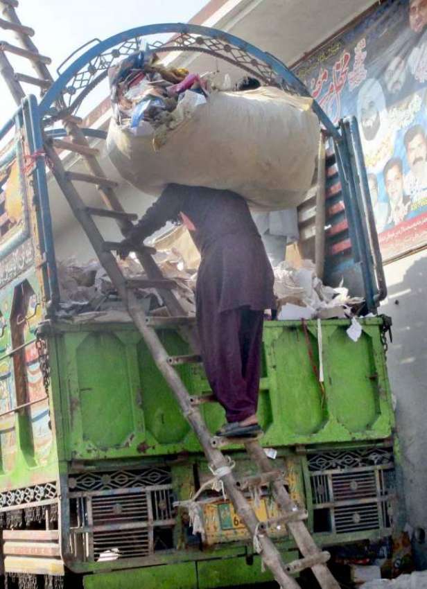 فیصل آباد: مزدور ٹرک پر ردی وغیرہ لوڈ کرنے میں مصروف ہے۔