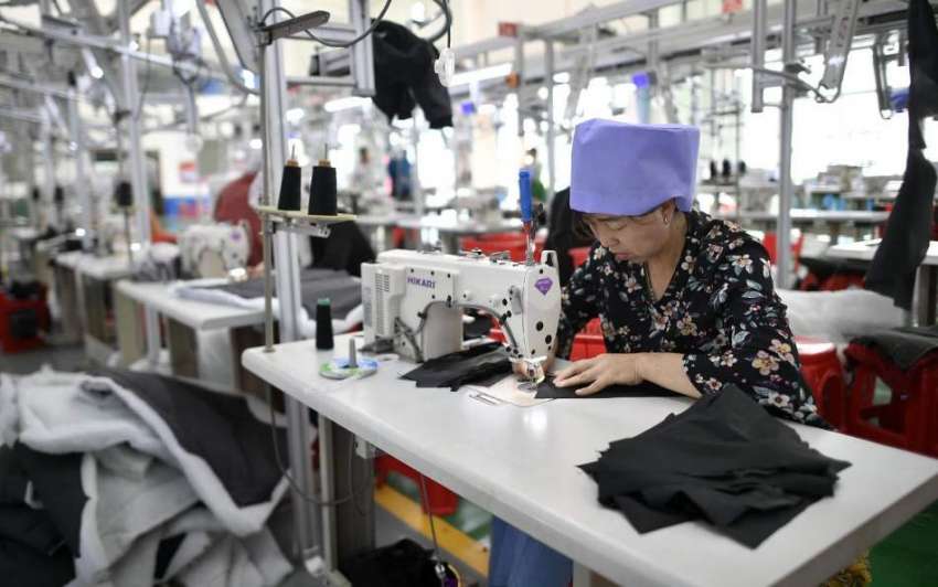 چین: خاتون محنت کش ٹیکسٹائل مل میں کپڑے سلائی کر رہی ہے۔