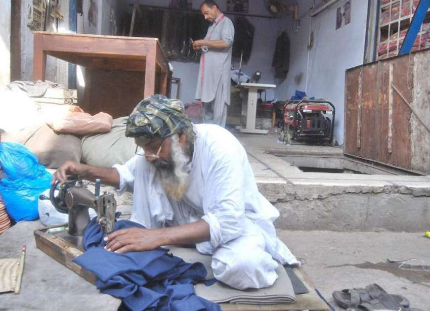 لاہور: ایک درزی بجلی کی لوڈ شیڈنگ کے باعث دکان کے باہر بیٹھا ..