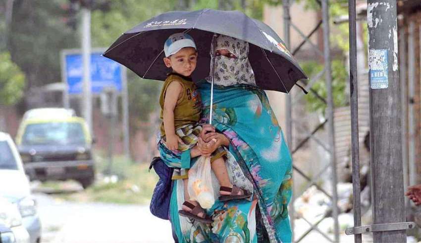 راولپنڈی: ایک خاتون اپنے بچے کے ہمراہ دھوپ کی شدت سے بچنے ..