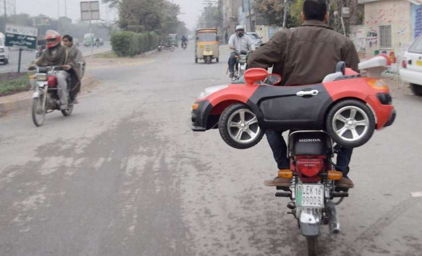 لاہور: موٹر سائیکل سوار شہری بچوں کے لیے چھوٹی گاڑی لیکر ..