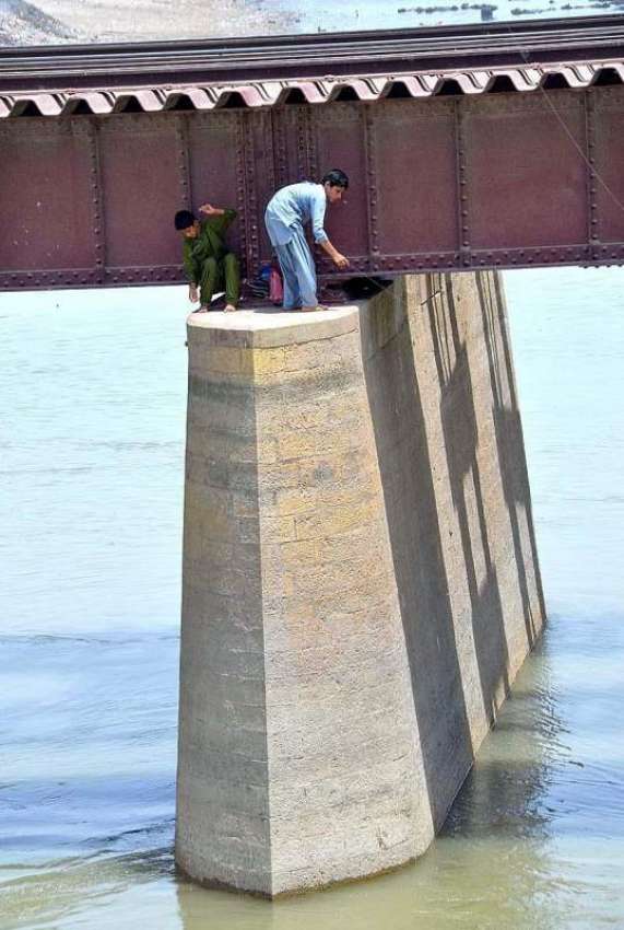 حیدر آباد: بچے ریلوے ٹریک کے پل پر بیٹھے مچھلیاں پکڑنے کی ..