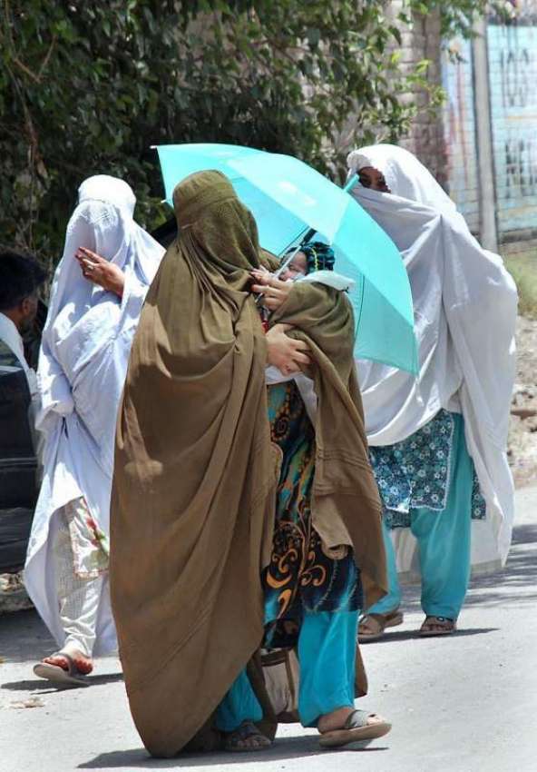 پشاور: ایک خاتون اپنے بچے کے ہمراہ گرمی اور دھوپ کی شدت سے ..