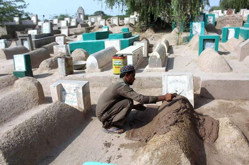 ملتان: مزدور قبر پر مٹی کا لیپ کر رہاہے۔