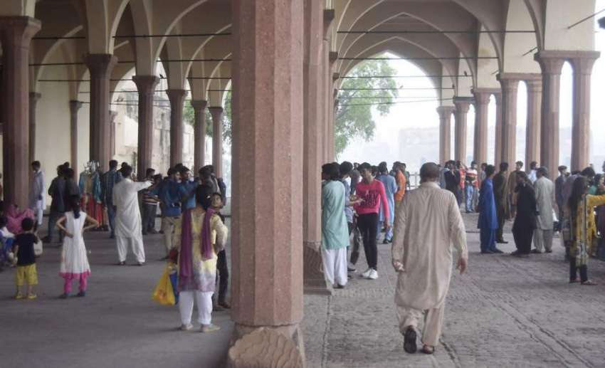 لاہور: شاہی قلعہ میں سیرو تفریح کے لیے آئے شہری بارش سے بچنے ..