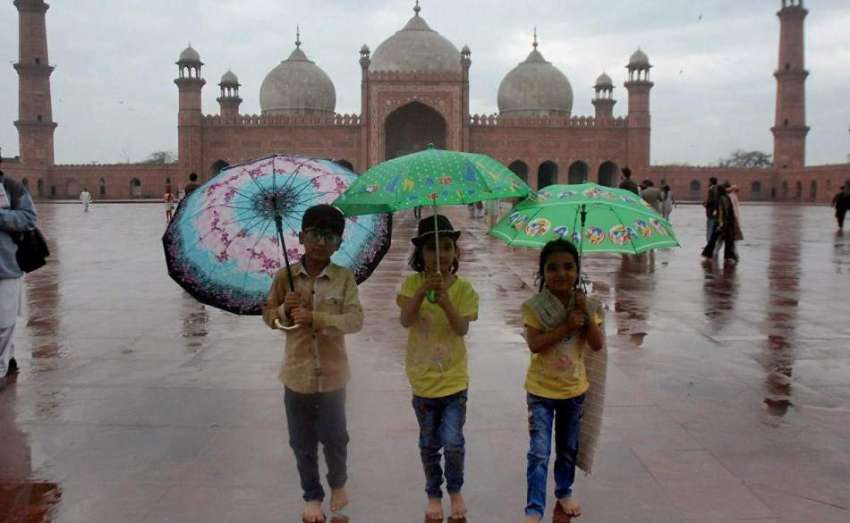 لاہور: بارش کے دوران بادشاہی مسجد میں بچے چھتریاں تانے صحت ..