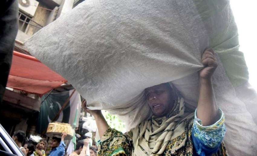 لاہور: محنت کش خاتون بھاری سامان اٹھائے جا رہی ہے۔