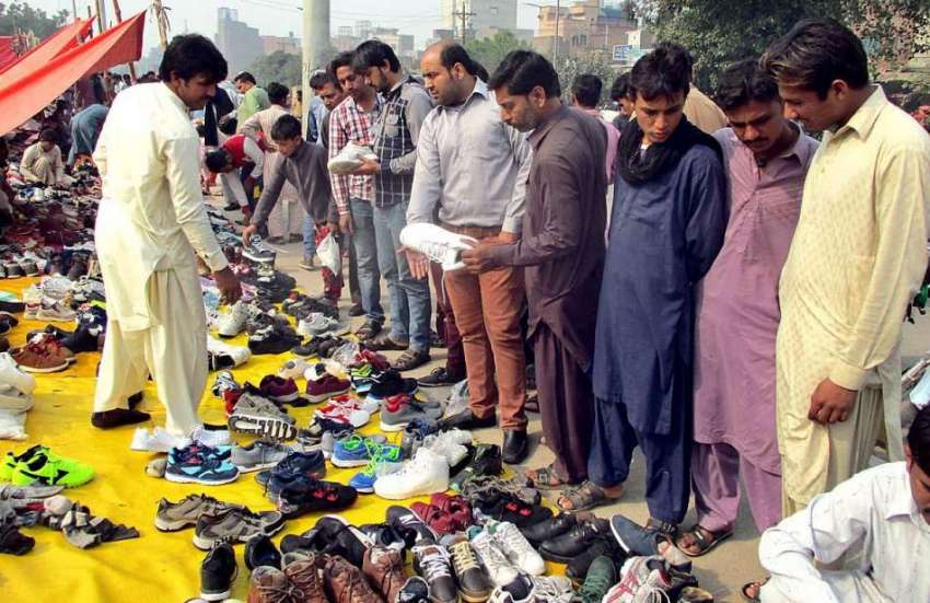 فیصل آباد: شہری سڑک کنارے لگے سٹال سے جوتے خرید رہے ہیں۔
