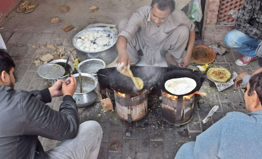 لاہور: ایک محنت کش فٹ پاتھ پر بیٹھا روٹیاں تیار کررہا ہے۔