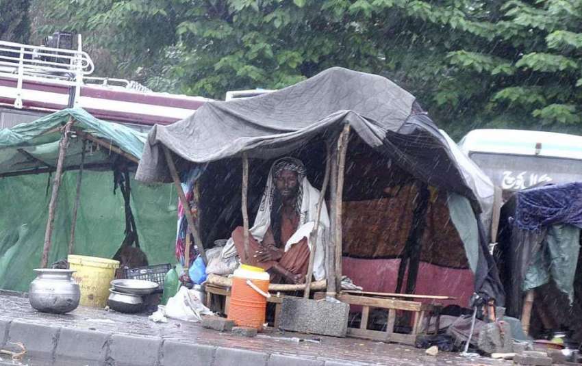 اسلام آباد: خانہ بدوش شخص بارش سے بچنے کے لیے اپنے خیمے میں ..