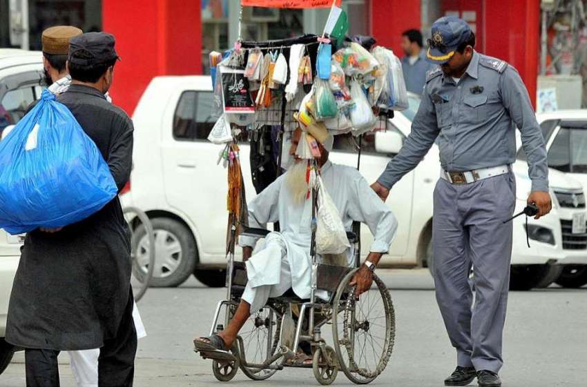 راولپنڈی: ٹریفک وارڈن معذور شخص کو سڑک کراس کررا رہا ہے۔