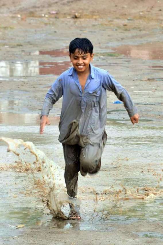 ملتان: بچہ بارش کے دوران کھیل کود میں مصروف ہے۔