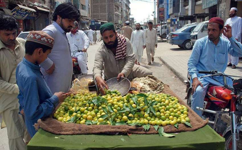پشاور: شہری ریڑھی بان سے لیموں خرید رہے ہیں۔
